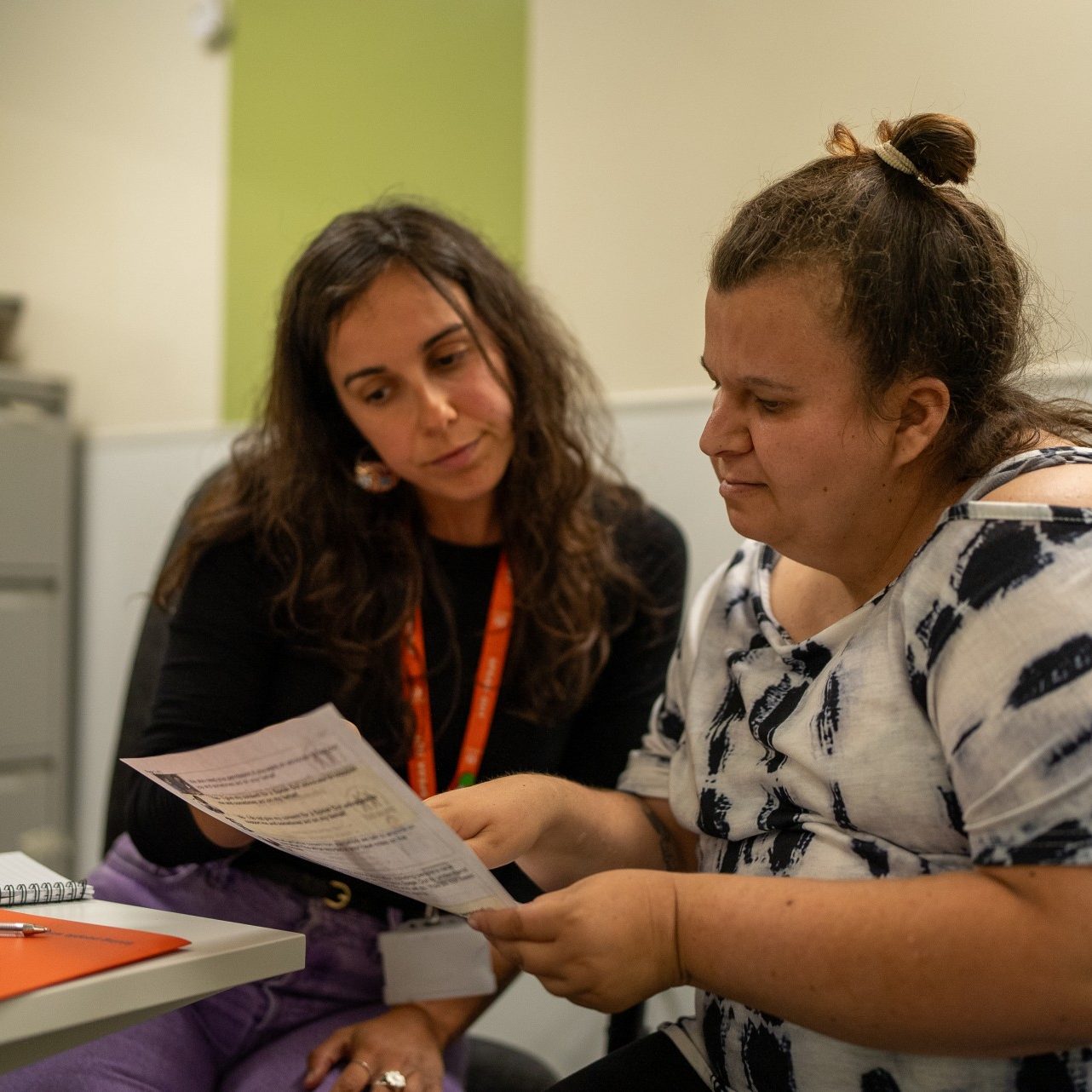 A person with a learning disability getting supported by a person to read an easy read document that has been translated by Speak Out